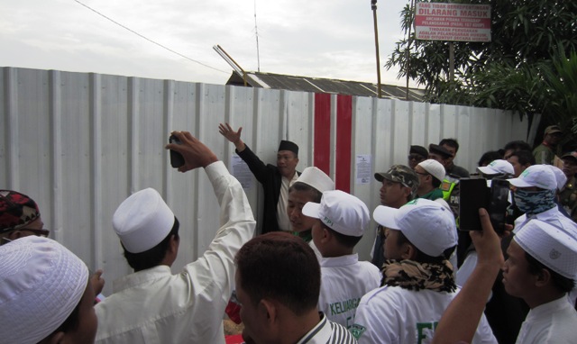Para peserta demo meminta petugas satuan polisi pamong praja untuk memasang spanduk di pintu gerbang proyek pembangunan gereja St Clara. (HIDUP/A. Nendro Saputro)