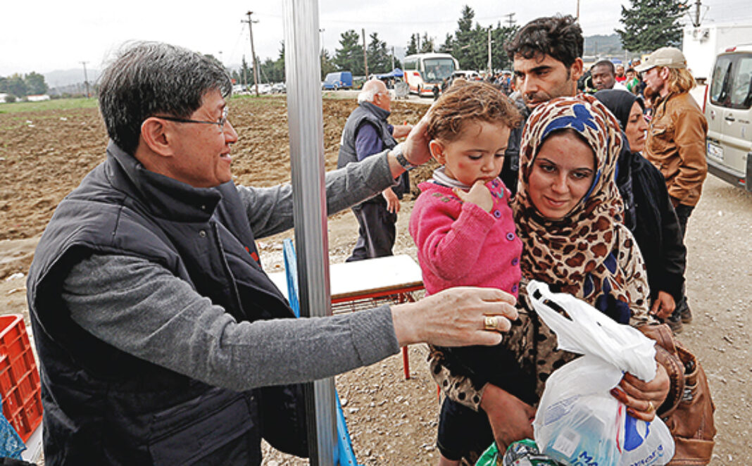 Cardinal Tagle greets family as refugees arrive at transit camp in Idomeni, Greece
