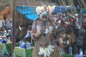 (Alm) Emerickus Sarkol menjadi MC di acara Festival Asmat Pokmat 35 (6-12 Oktober 2023) saat acara lelang karya seni ukir dan anyaman yang dibuat masyarakat Asmat. (HIDUP/Felicia Permata Hanggu)